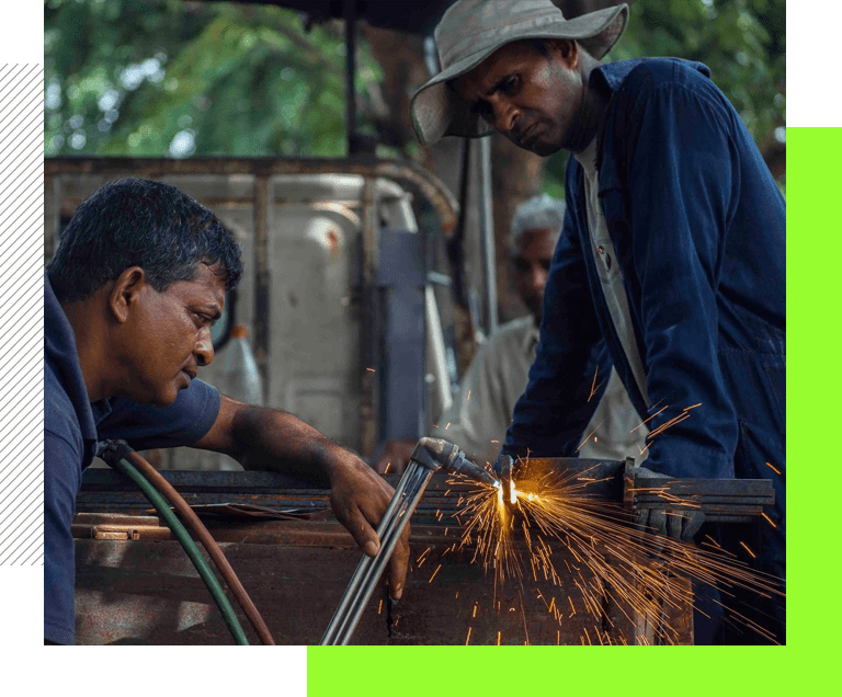 A man is welding something in the street.